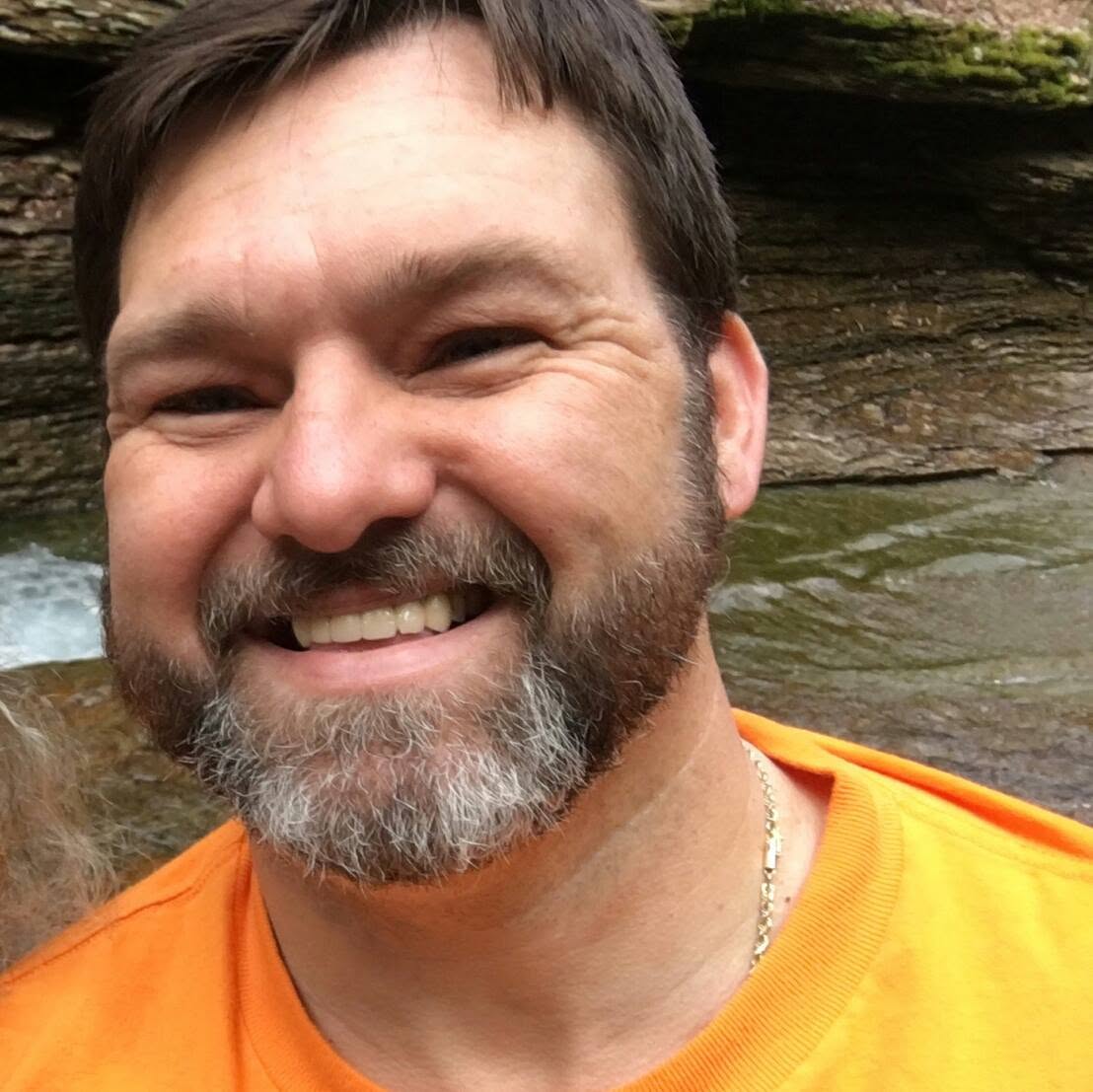 Eddie Fannin smiling outdoors by a creek