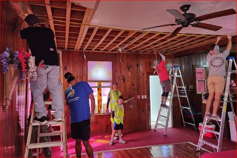 Volunteers rebuilding a Fort Myers home after Hurricane Ian, repairing the ceiling and walls