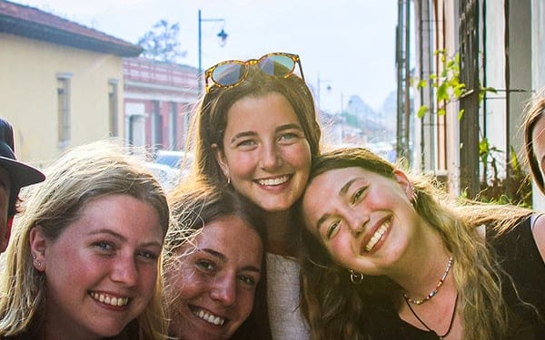 Group of Ambassador teen volunteers smiling together on a sunlit town street