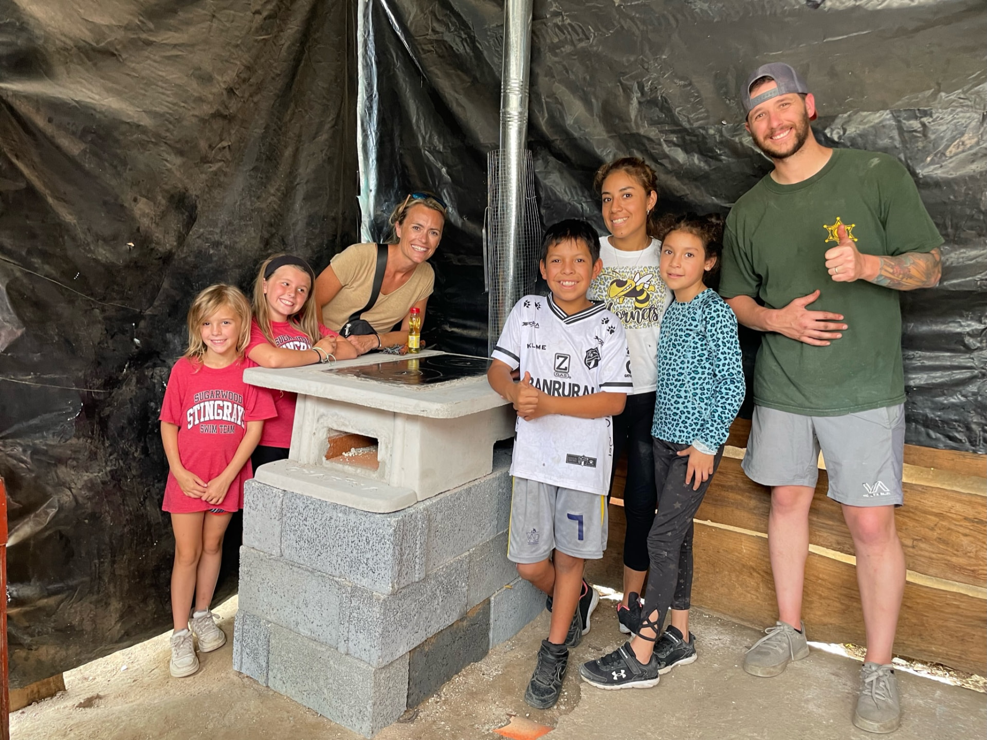 Volunteer family and Guatemalan children beside a newly built cook stove