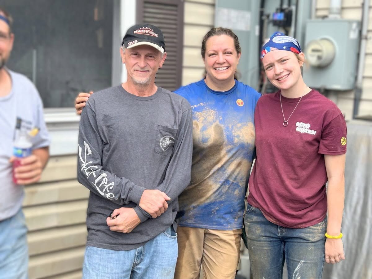 Homeowner standing arm in arm with two volunteers