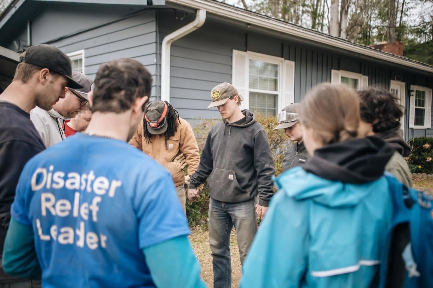Volunteer team praying together in a circle outside a home