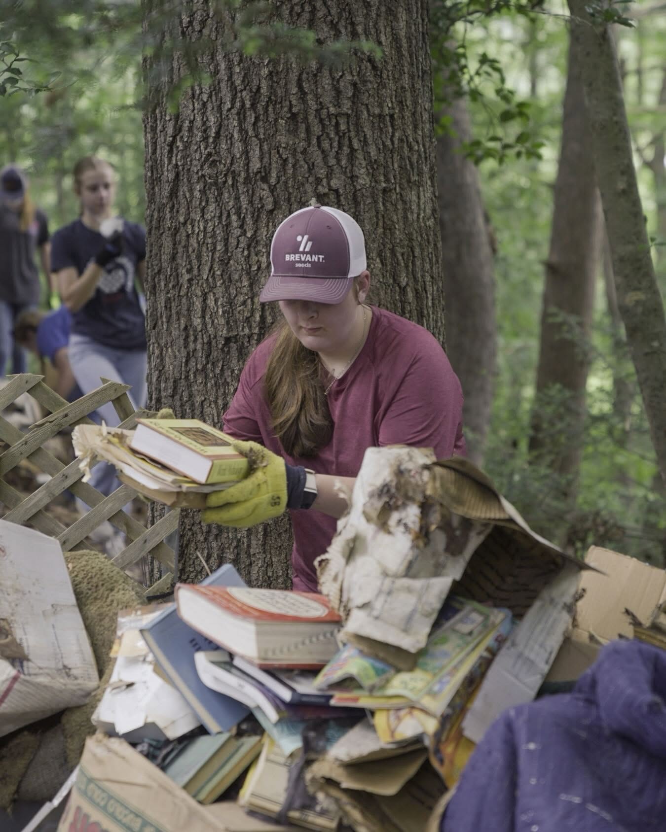 Volunteer clearing water-damaged books from a debris pile